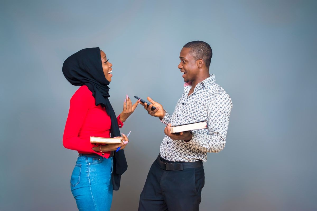 young black man and woman carrying books having a friendly conversation